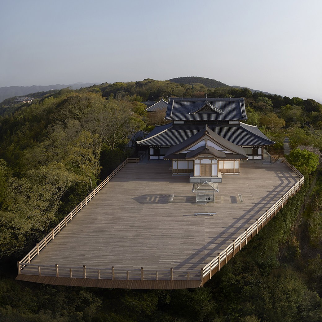 木々の茂る山の上に建つ青龍殿の大きな木の舞台を、上空から見た景色。舞台の上にガラスの茶室が置かれている。